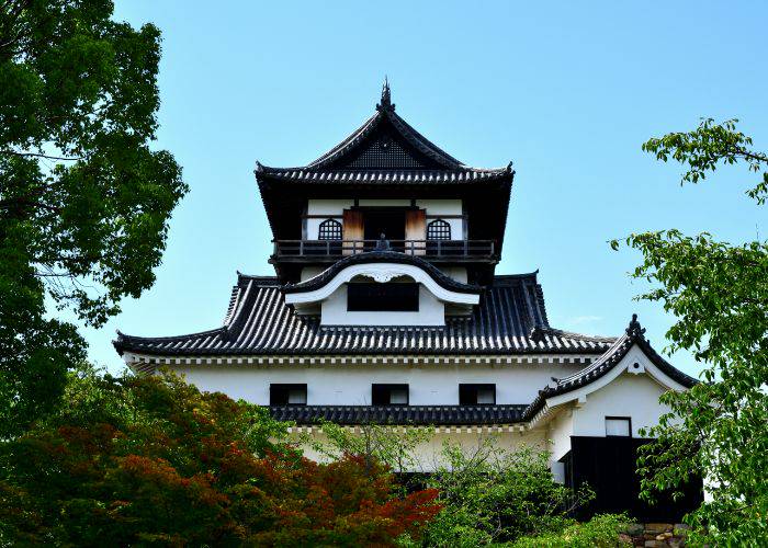 Looking up at Inuyama Castle, black and white against a blue sky.